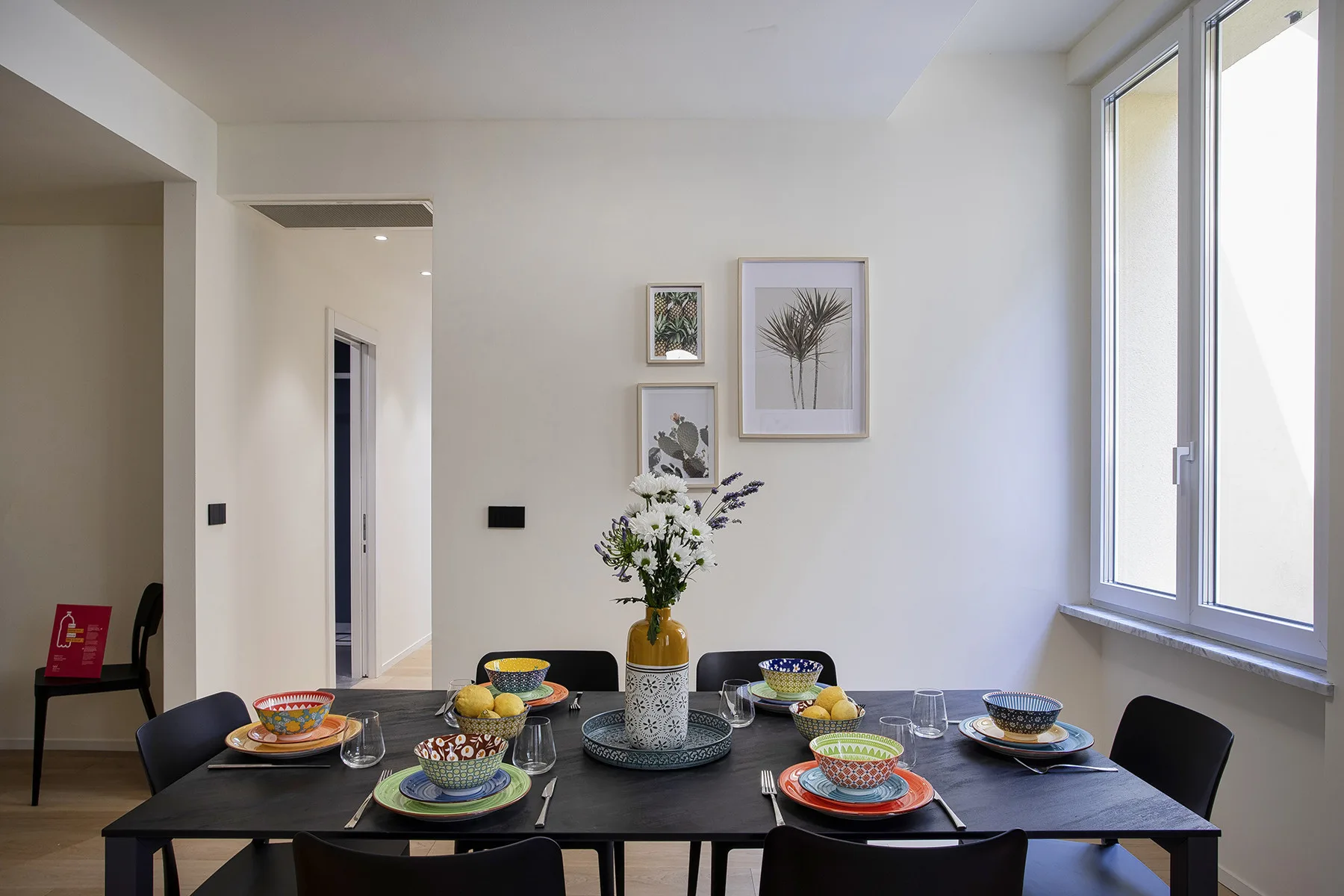 Comedor con una mesa puesta y láminas botánicas enmarcadas en la pared.
