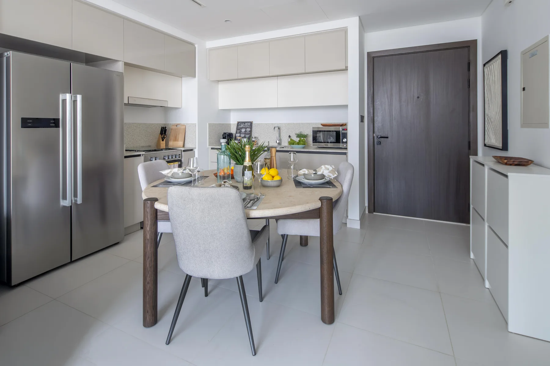 A bright dining area with a set table beside a modern kitchen.