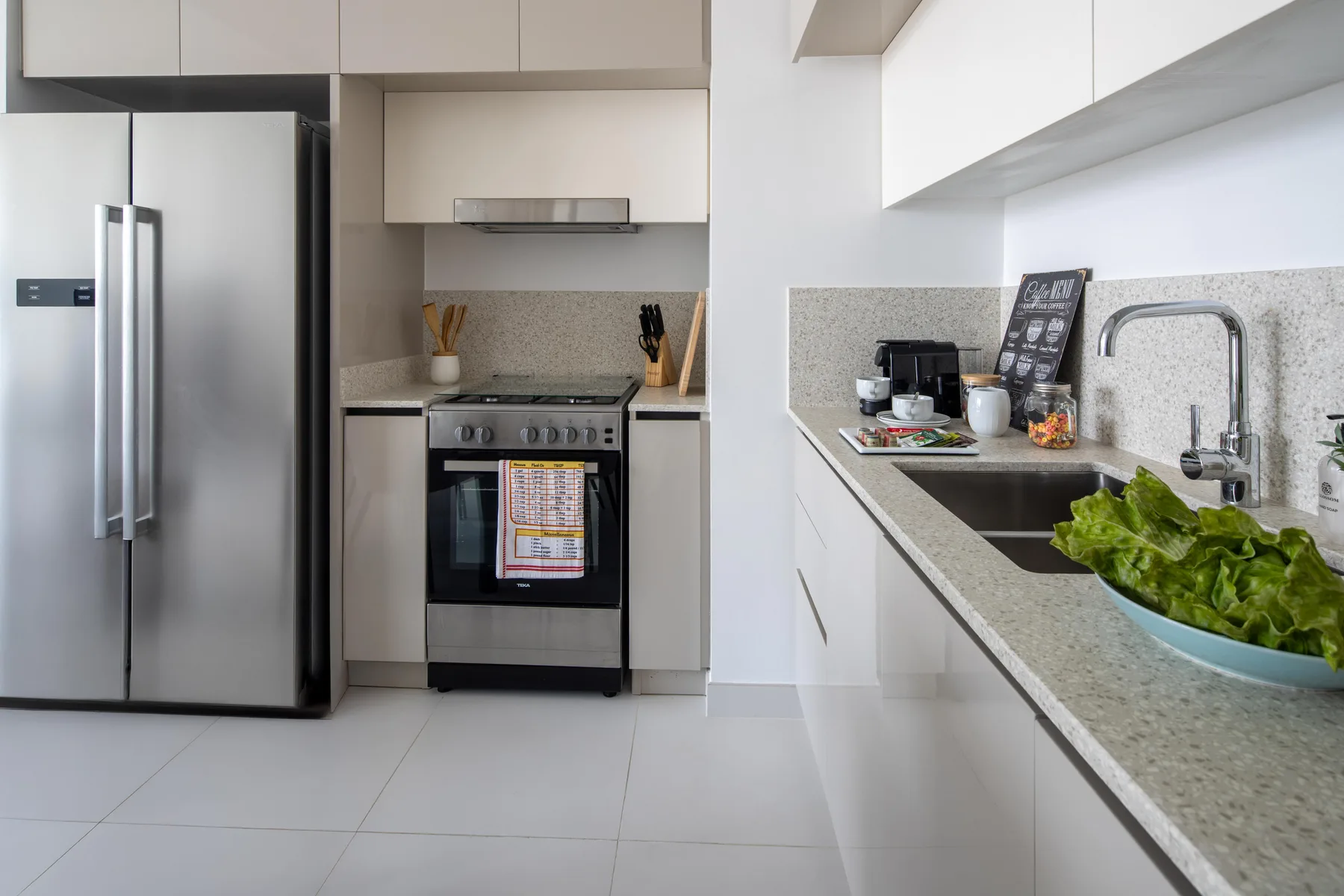 A modern kitchen with stainless steel appliances and a long countertop.