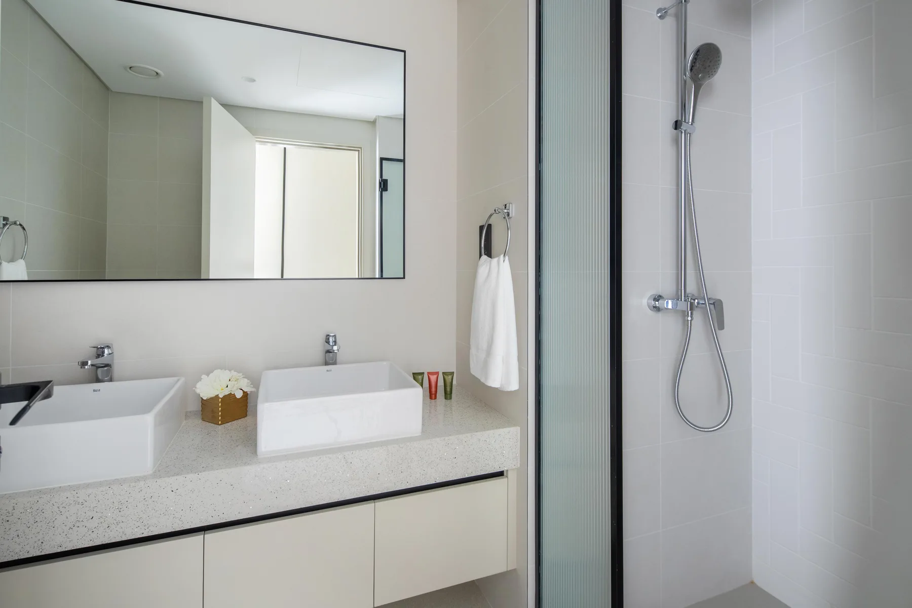 A bright bathroom with a wide vanity and a wall-mounted shower.