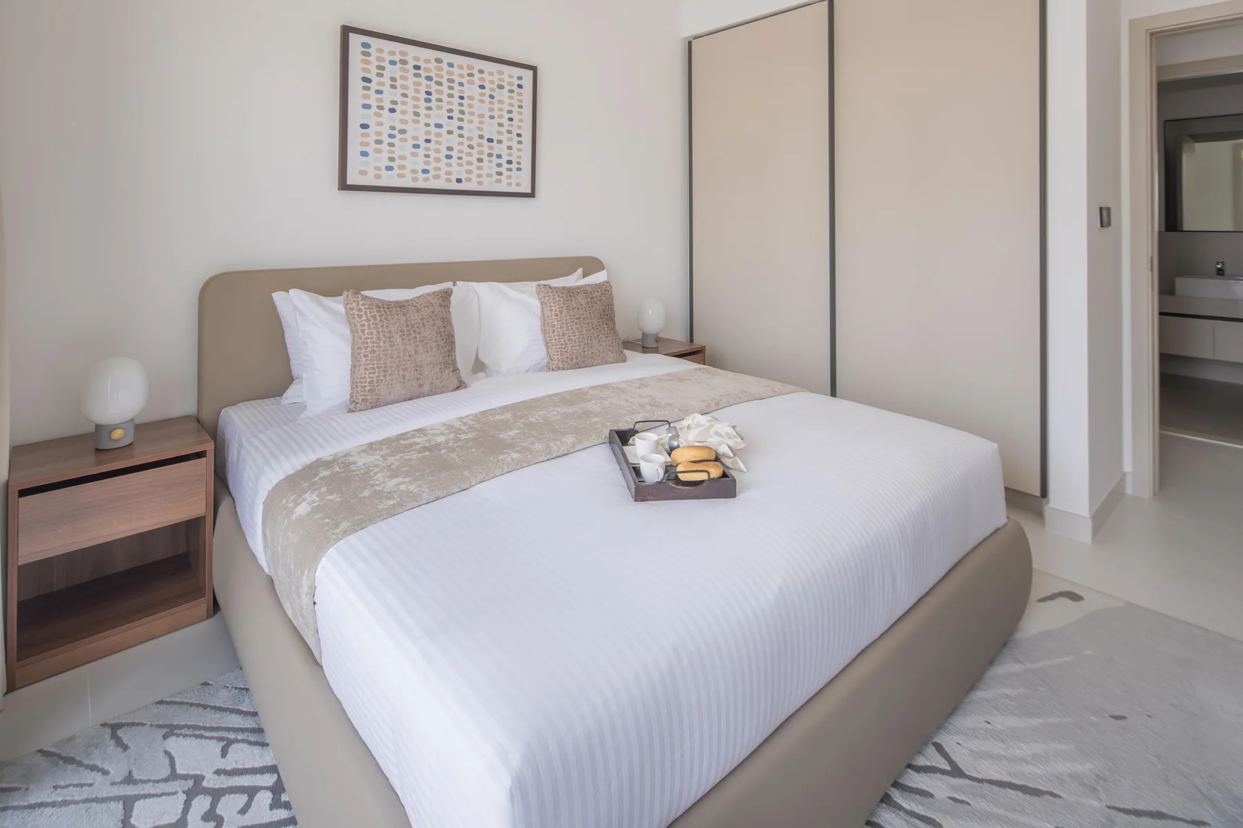 A bedroom with a neatly made bed and a framed print above the headboard.