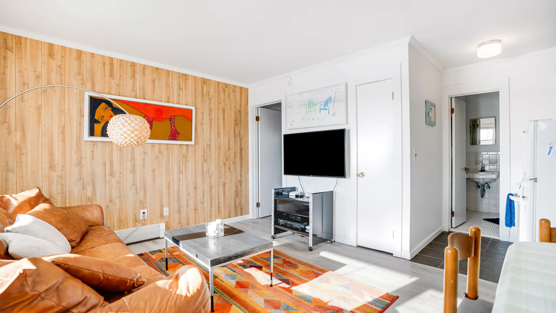 A living room with seating, a television, and a colorful area rug.