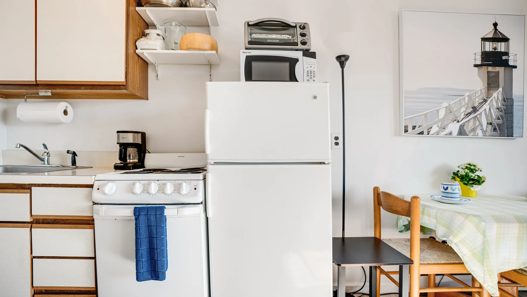 A compact kitchen with a refrigerator, stove, and small dining table.
