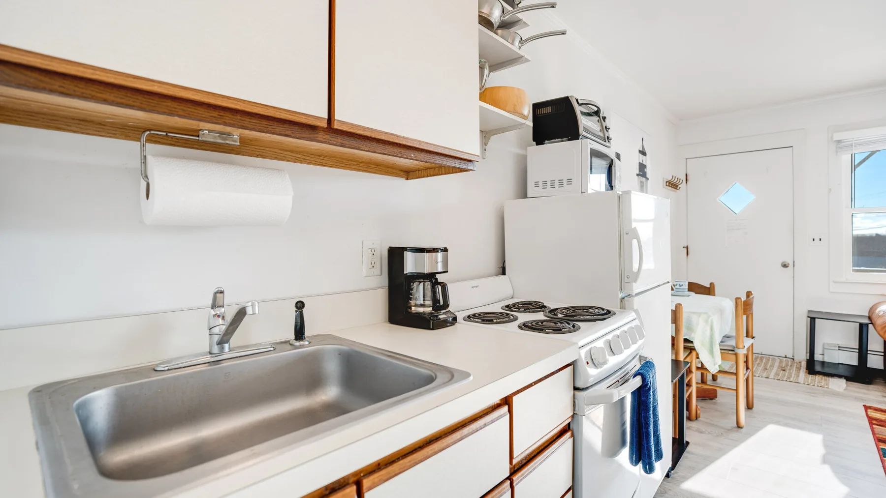 A bright kitchen with a sink, stove, and dining table by the window.