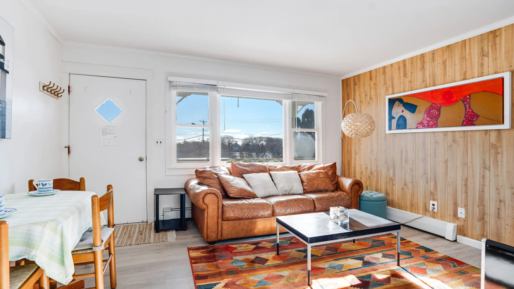 A living room with a brown sofa and colorful rug.