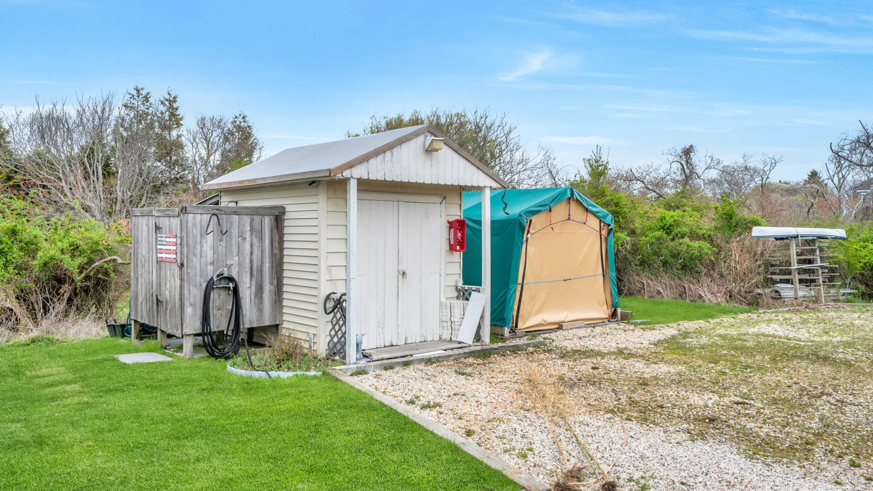 A small outdoor shed stands beside a green lawn and a gravel path.