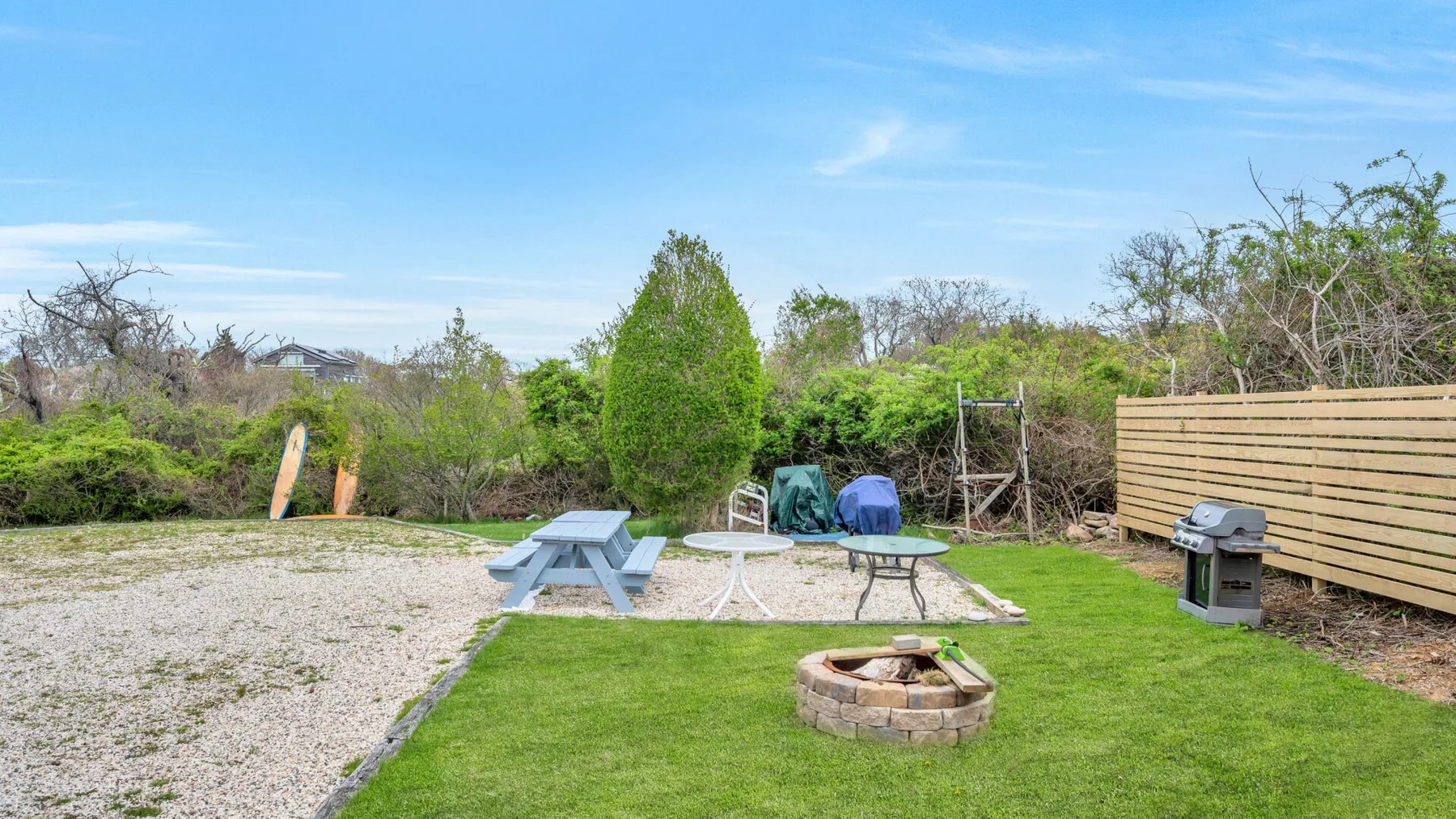 An outdoor picnic area with a table, seating, and a fire pit.
