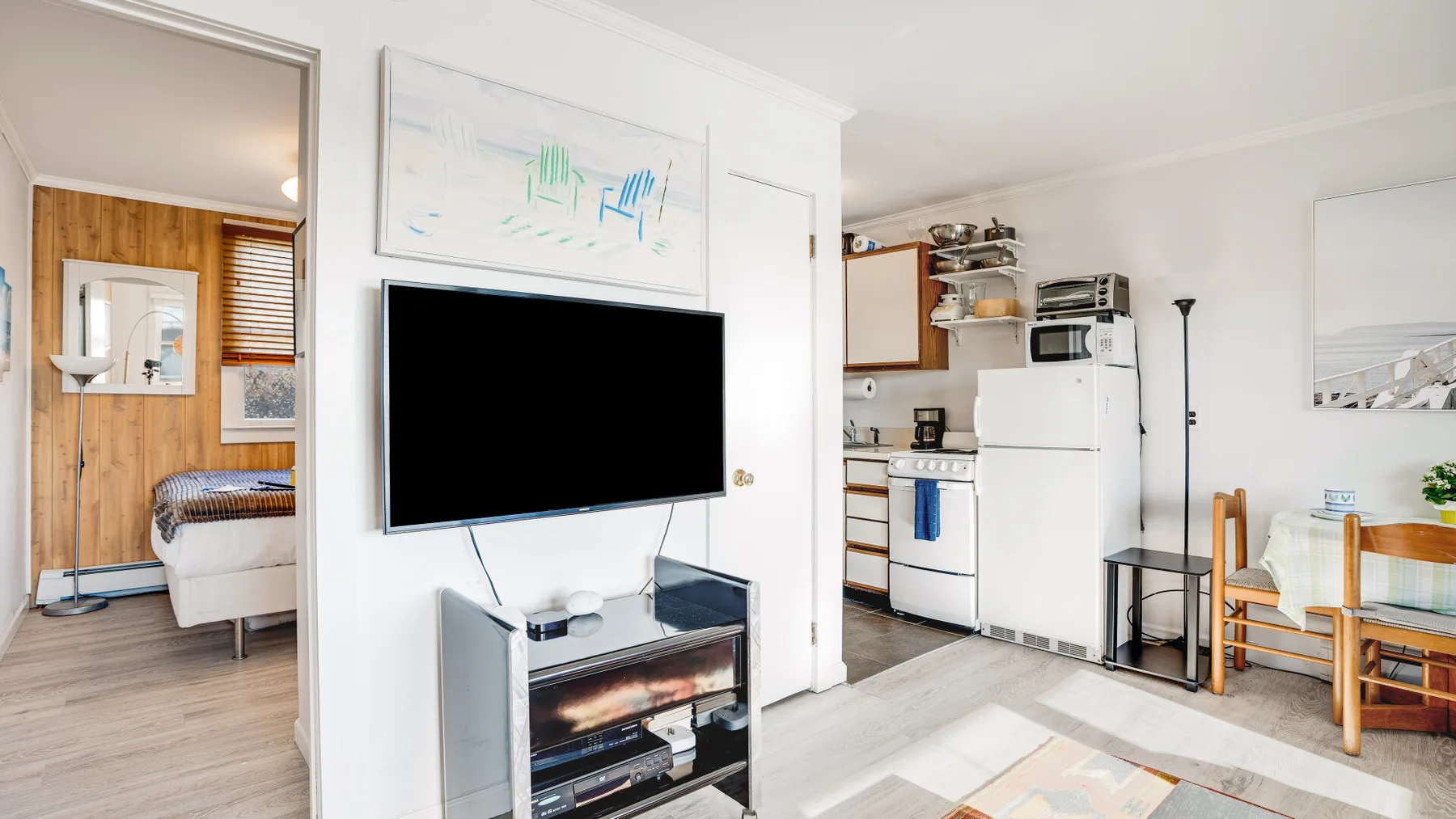A living area with a television and an adjoining kitchen.