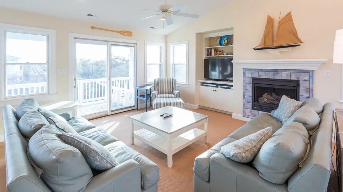 A bright living room with seating, a coffee table, and a fireplace.