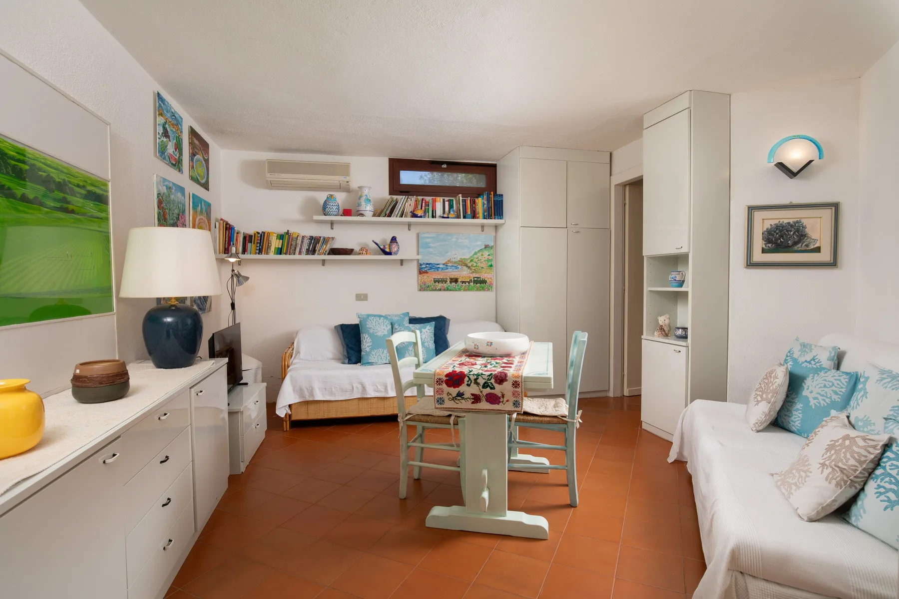 Una sala luminosa con asientos, estanterías y una pequeña mesa de comedor.