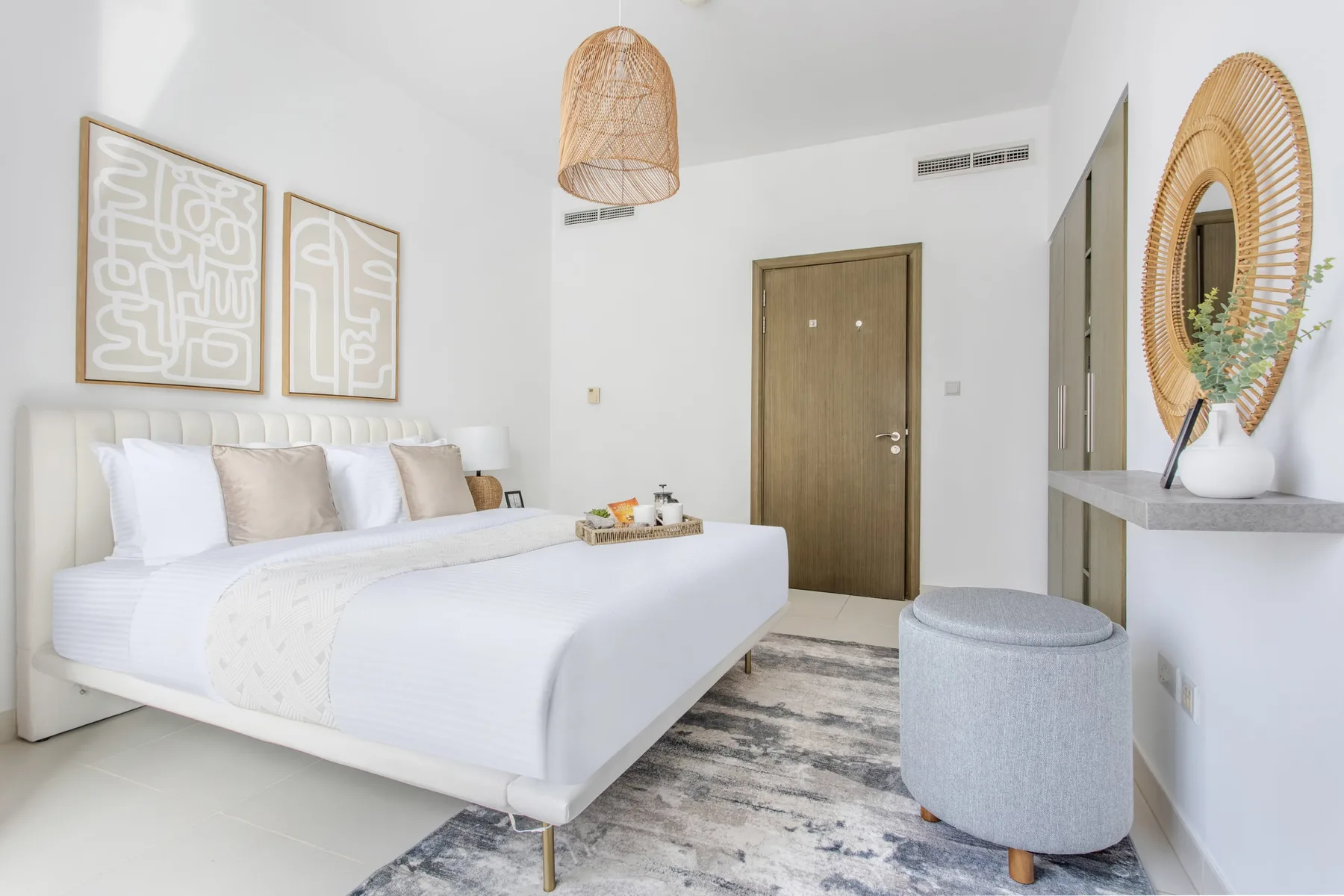 A bright bedroom with a neatly made bed and woven pendant light.