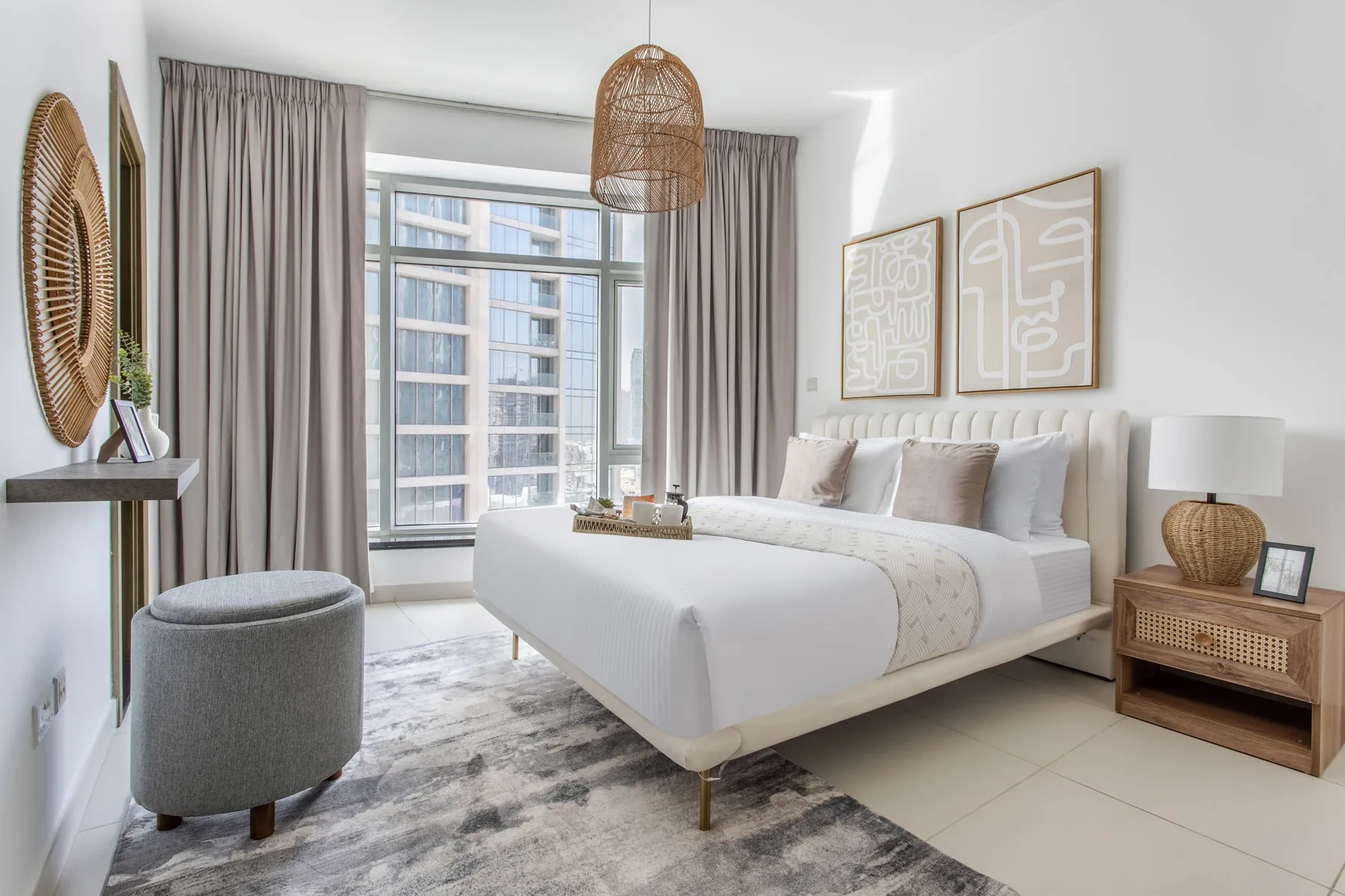A bright bedroom with a neatly made bed beside a large window.
