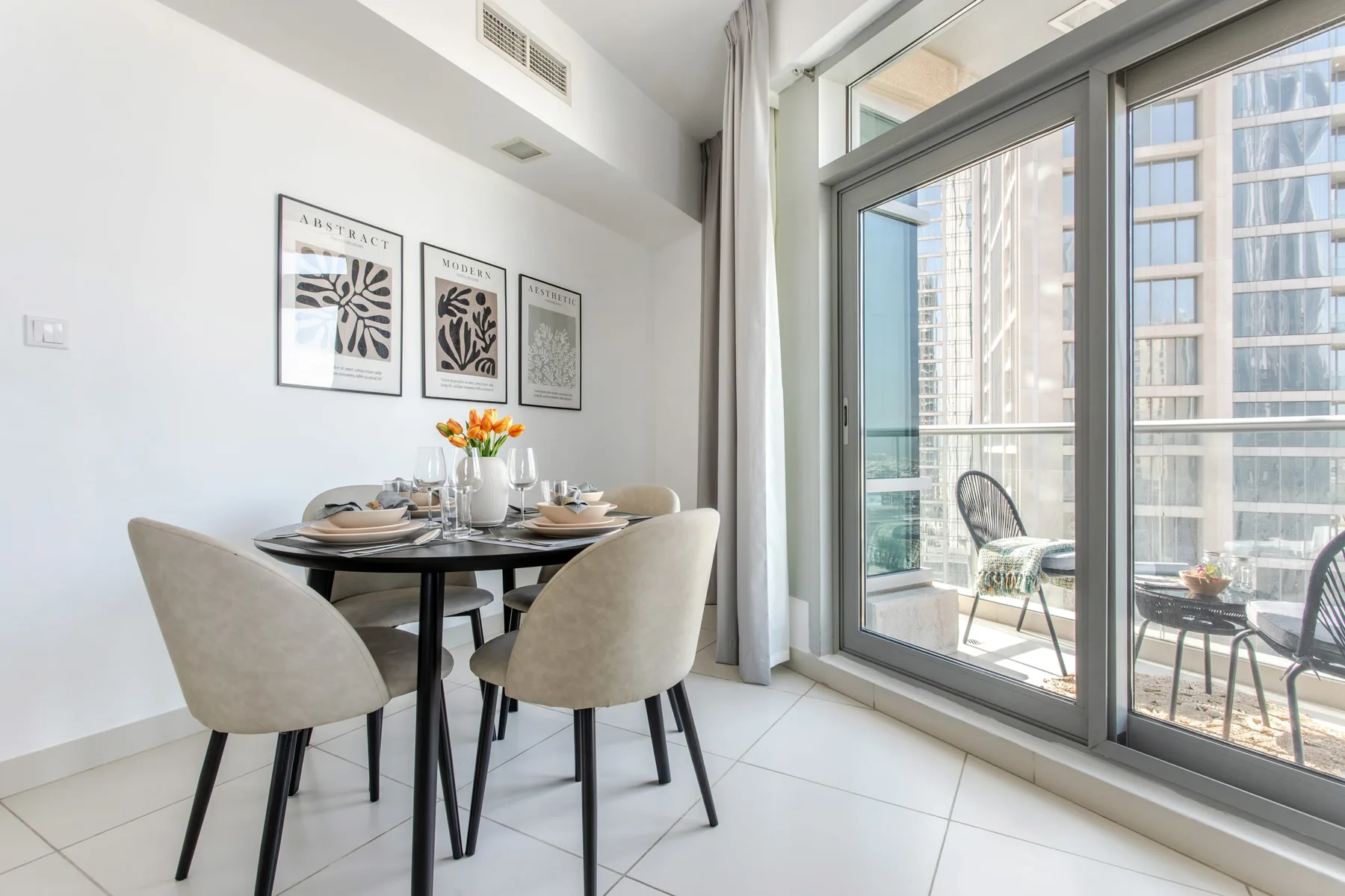 A dining area with a set table beside floor-to-ceiling windows.