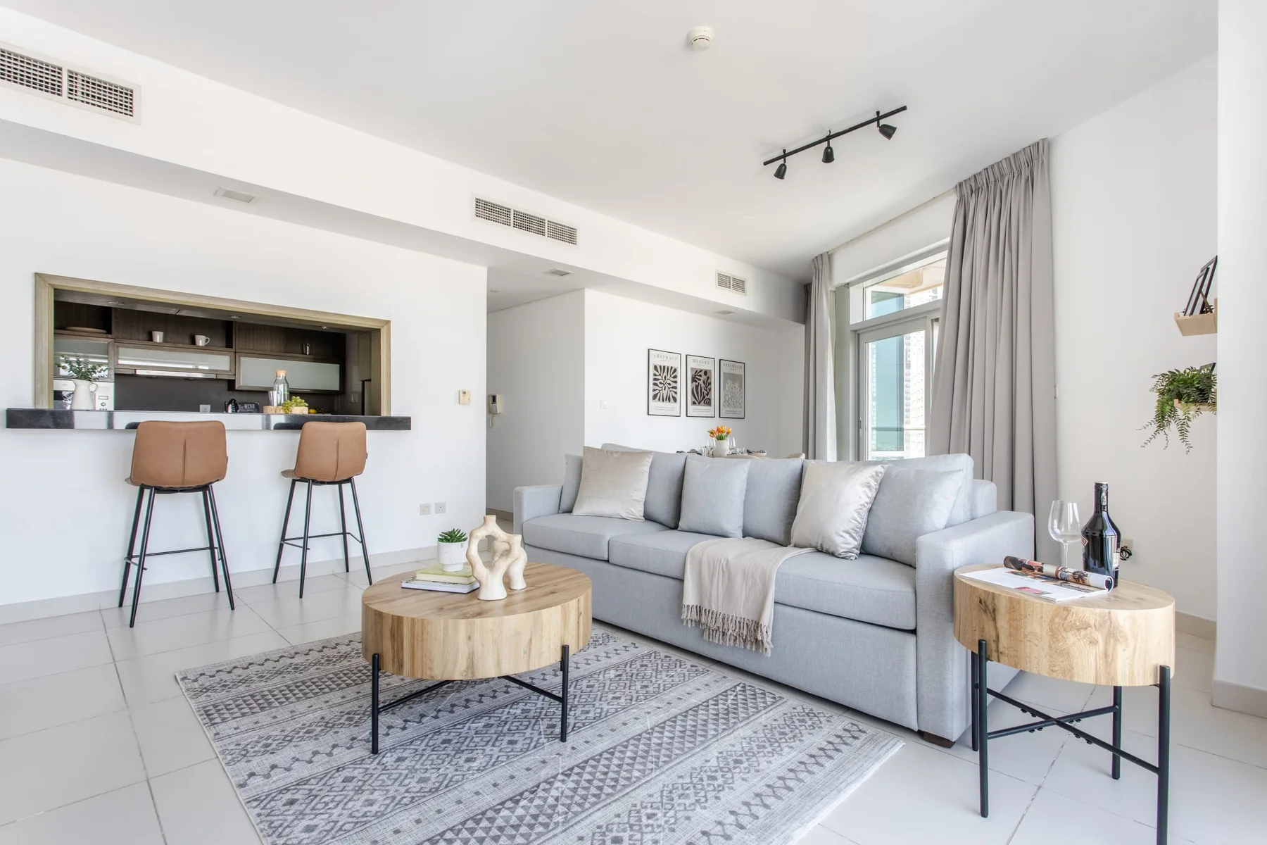 A bright living room with a gray seating area, coffee table, and kitchen counter.