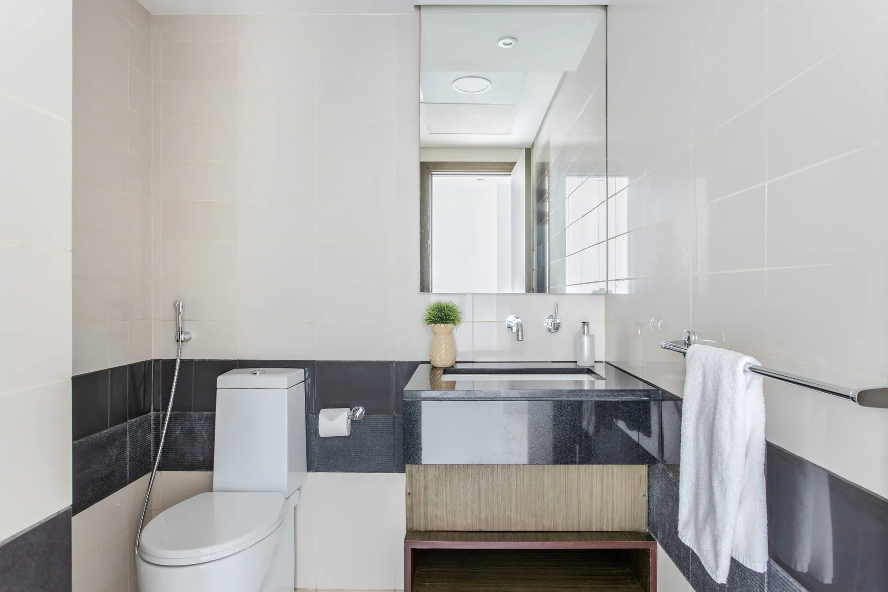 A tiled bathroom with a toilet, vanity, mirror, and white towels.