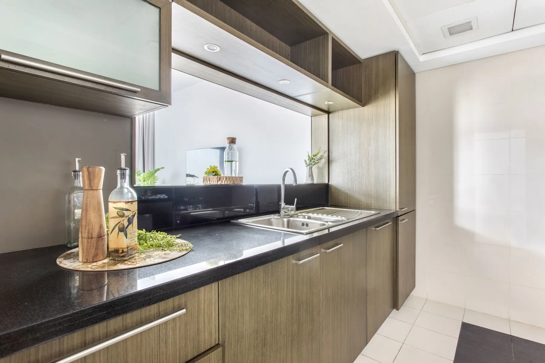 A modern kitchen with a dark countertop, sink, and overhead cabinets.