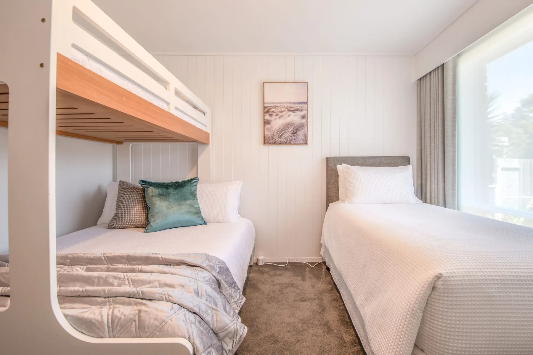 Un dormitorio luminoso con dos camas y una ventana grande.