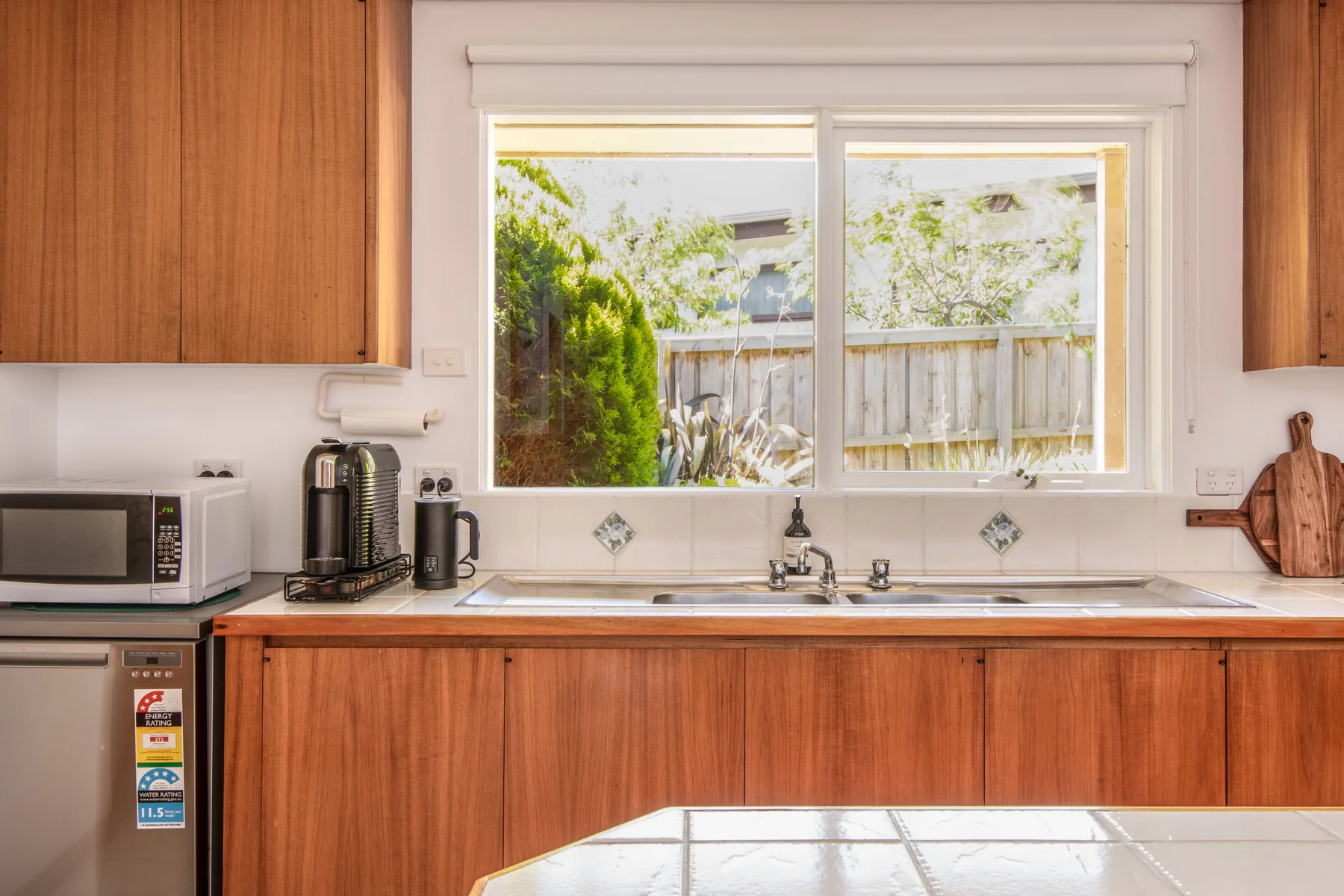 Una cocina con gabinetes de madera, un fregadero y una ventana con vegetación.