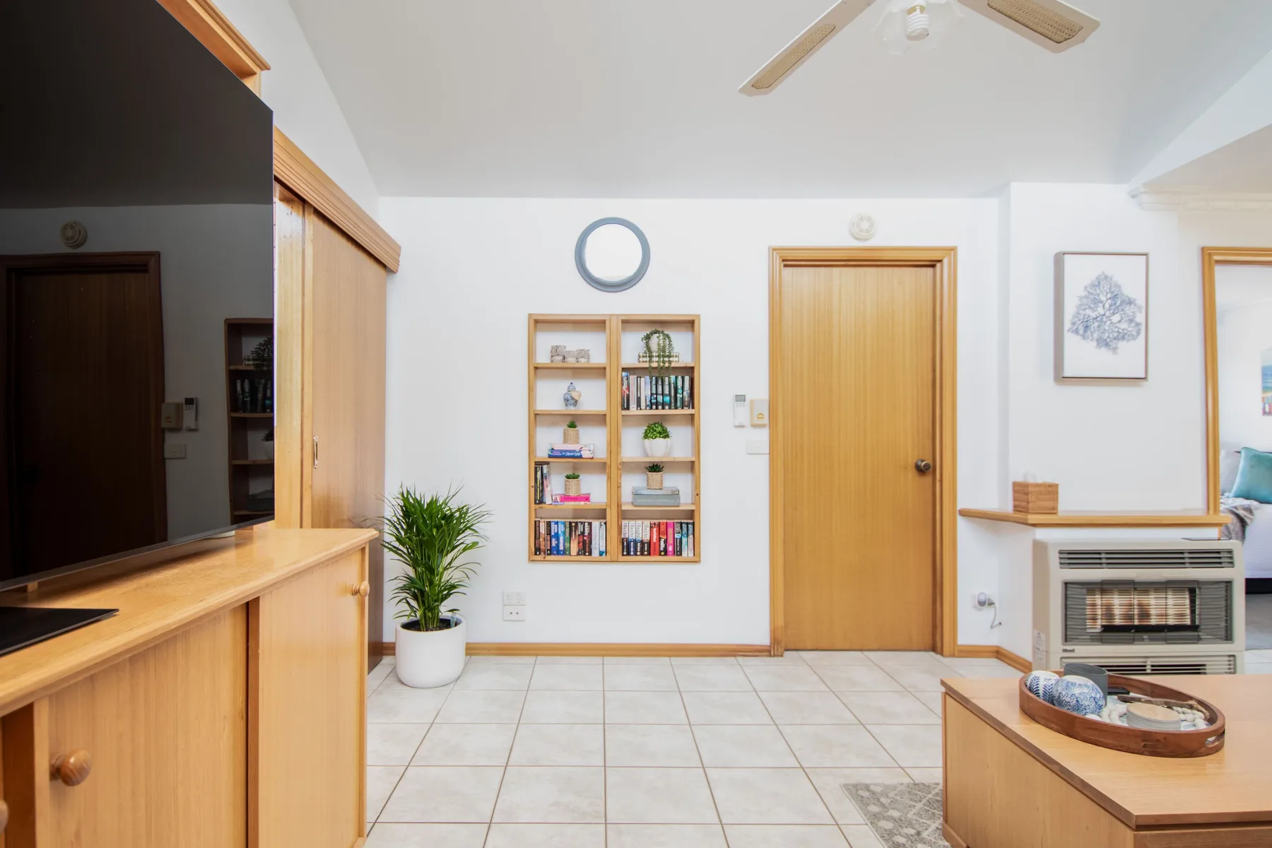 Una sala luminosa con muebles de madera, una estantería y un ventilador de techo.