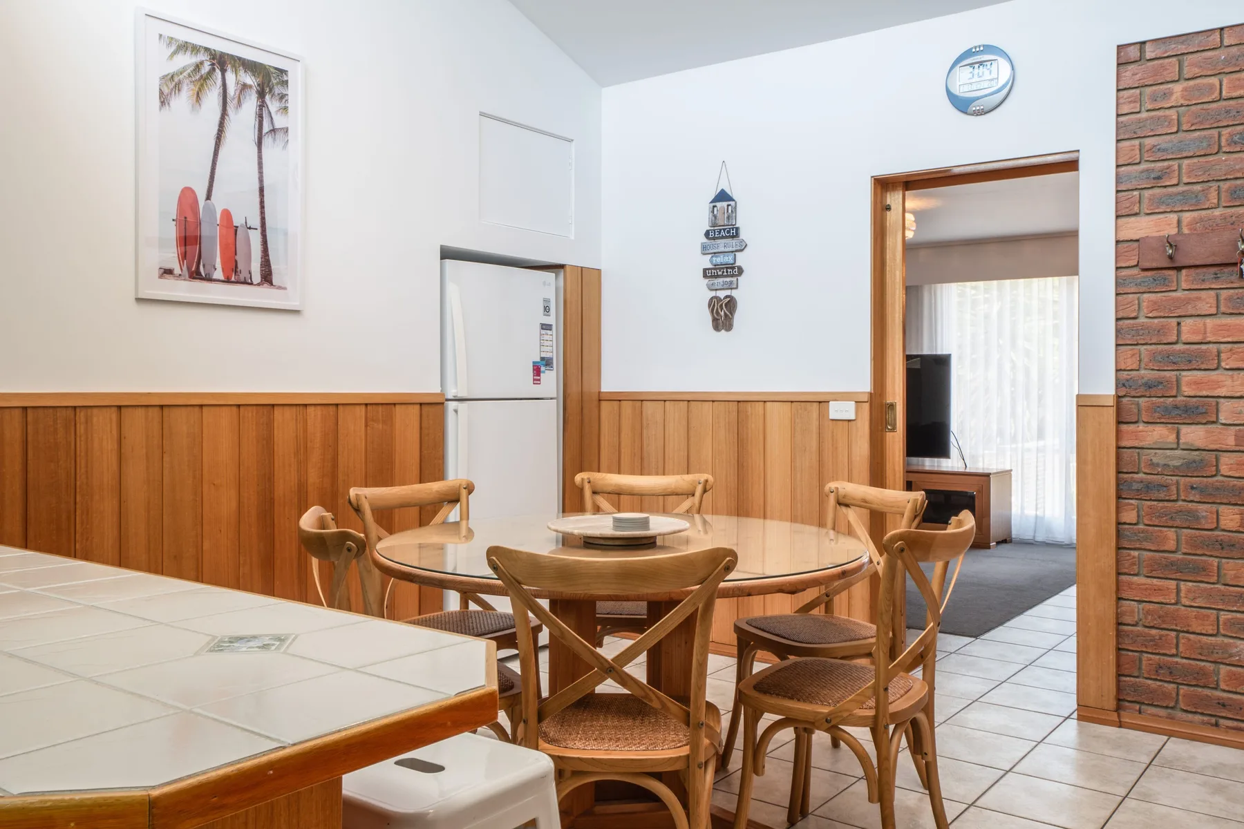 Un comedor con una mesa redonda y asientos de madera junto a una barra alicatada.