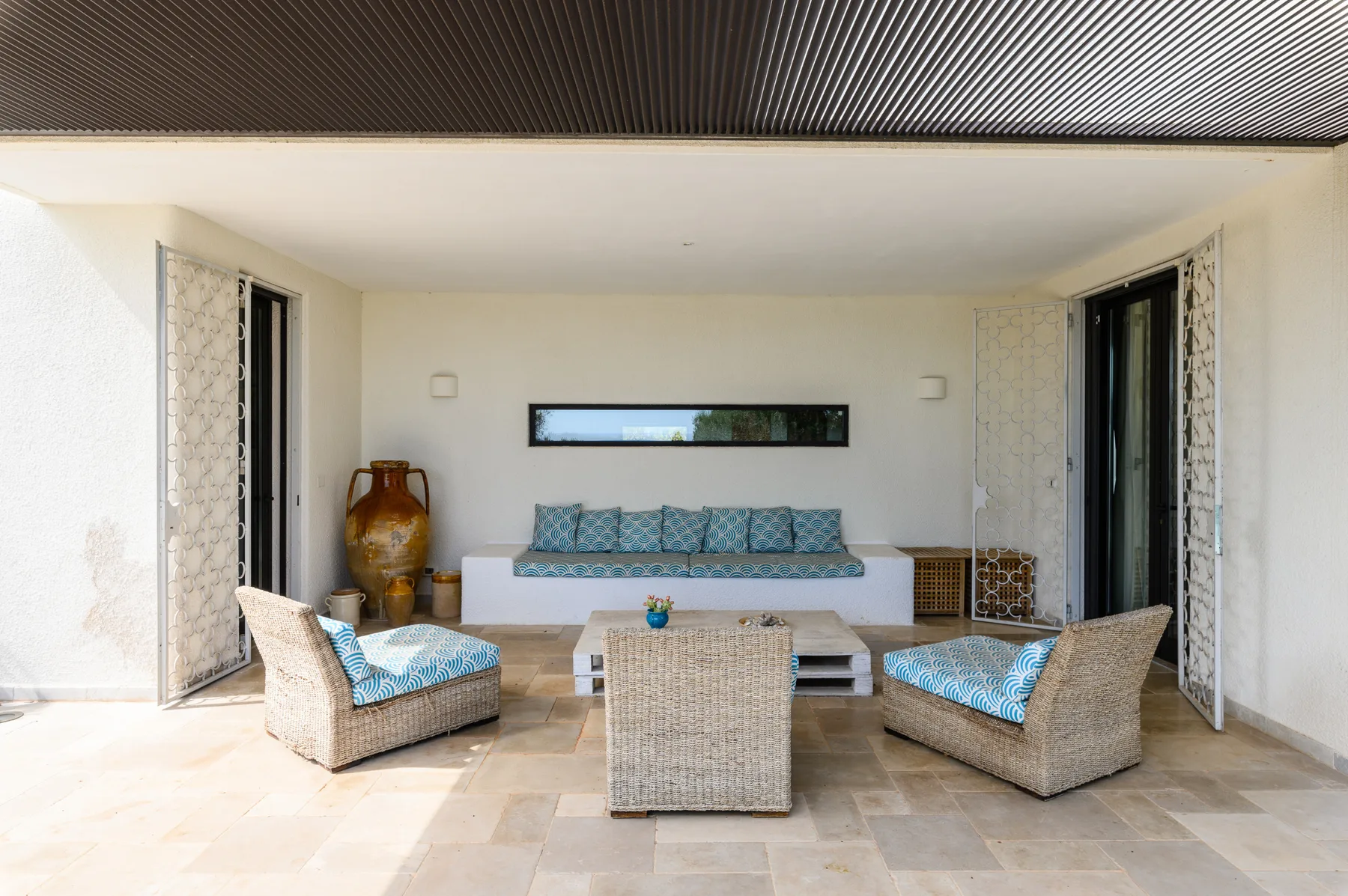 A covered patio lounge with wicker seating and a low central table.