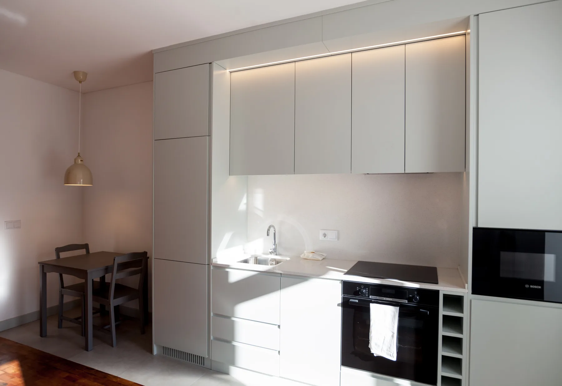 A compact kitchen with a sink, cooktop, and dining table.