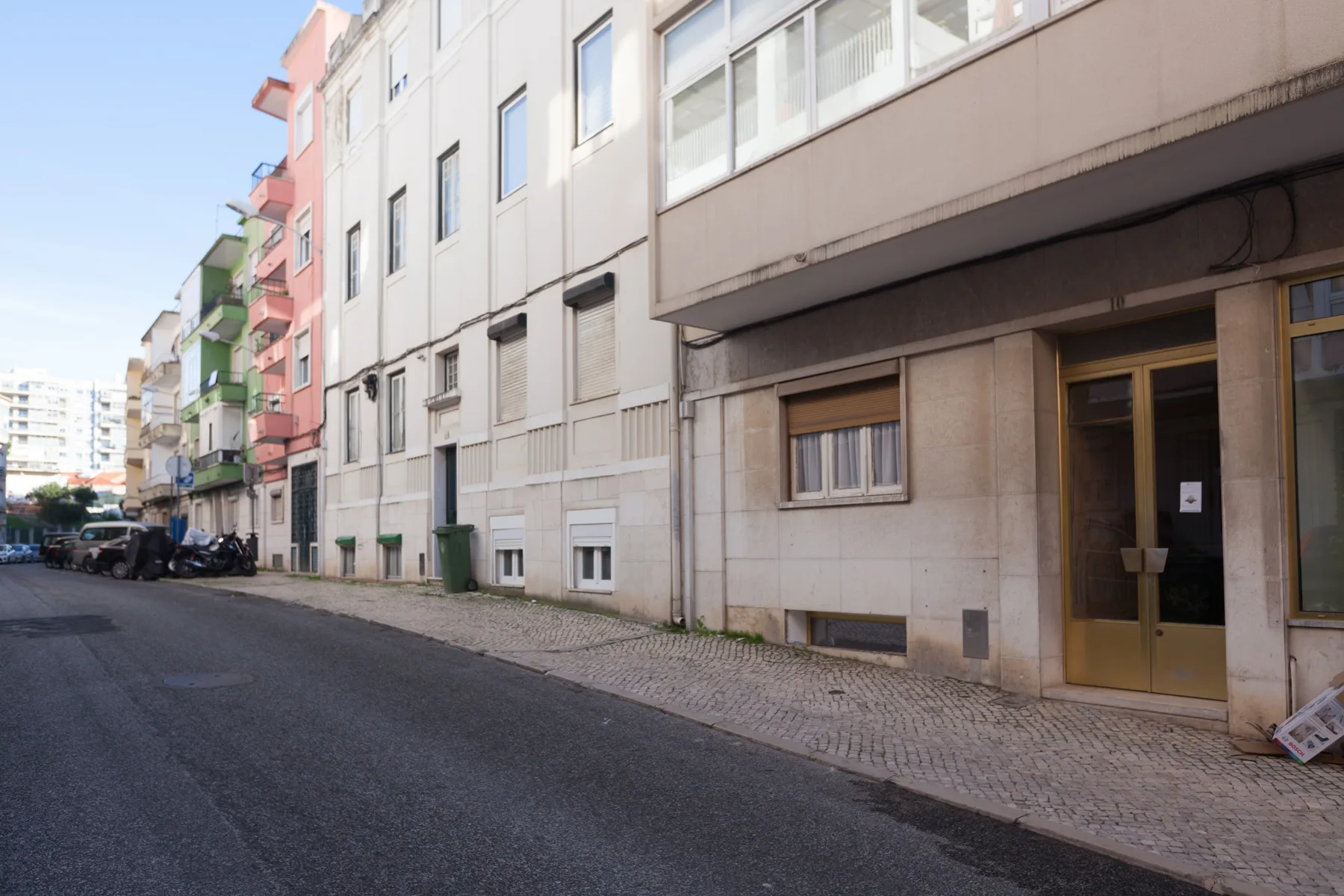 Street view of a row of apartment buildings with a paved sidewalk.