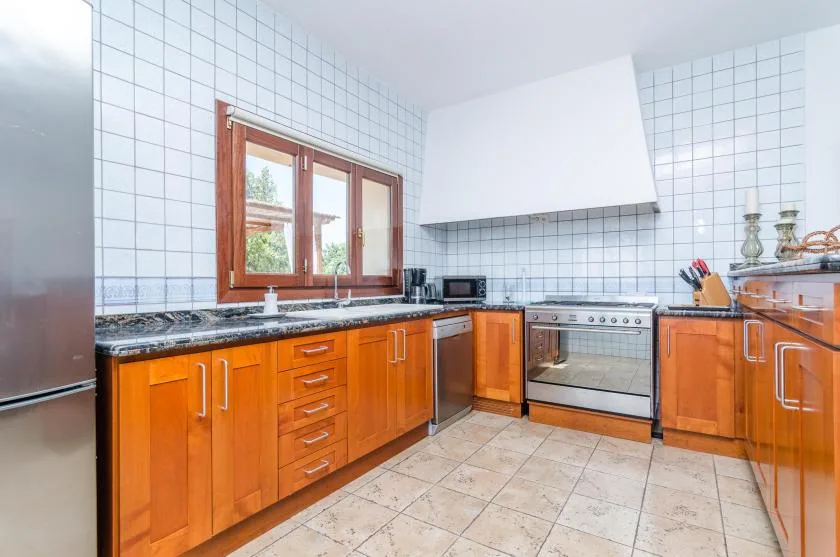 Una cocina con azulejos, gabinetes de madera, una encimera y una estufa.