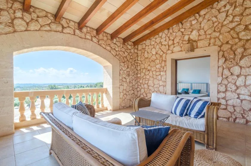 Un patio cubierto con paredes de piedra tiene asientos acolchados y una vista abierta.