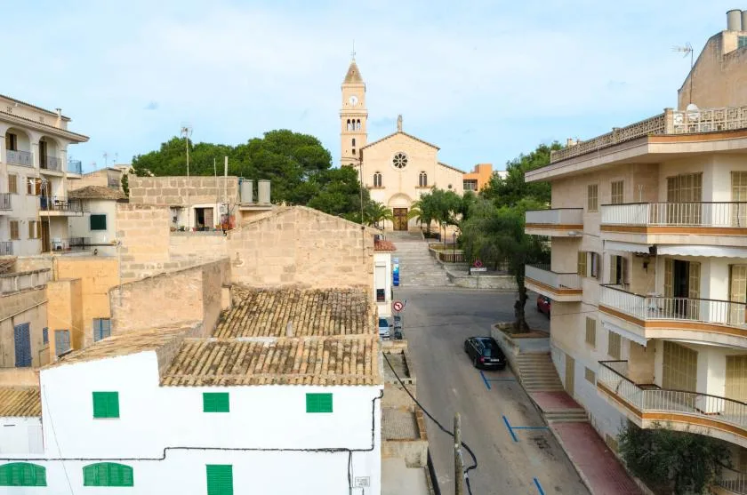 Una calle del pueblo pasa entre edificios y conduce a una iglesia con campanario.