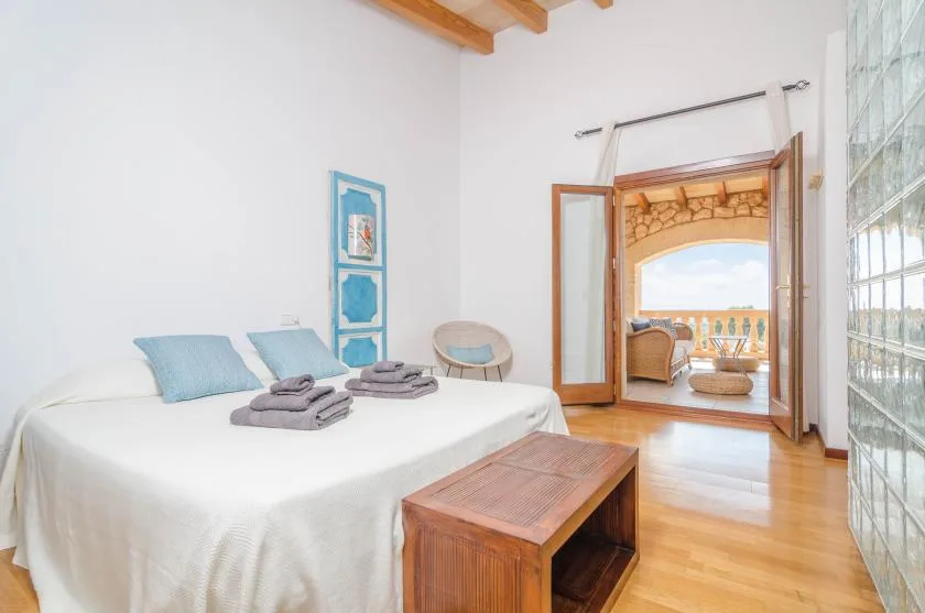 Un dormitorio luminoso con una cama y una puerta abierta que da a un balcón.