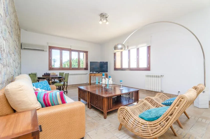 Una sala luminosa con una mesa de centro de madera y asientos de mimbre.