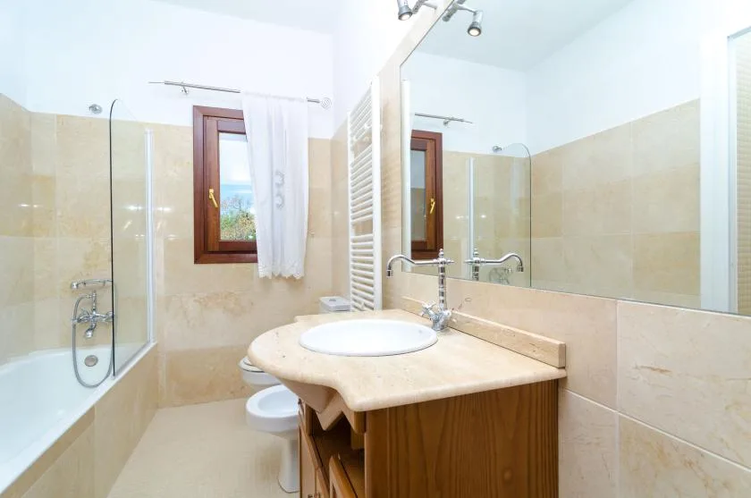 Un baño luminoso con lavabo, espejo y ducha con mampara de vidrio.