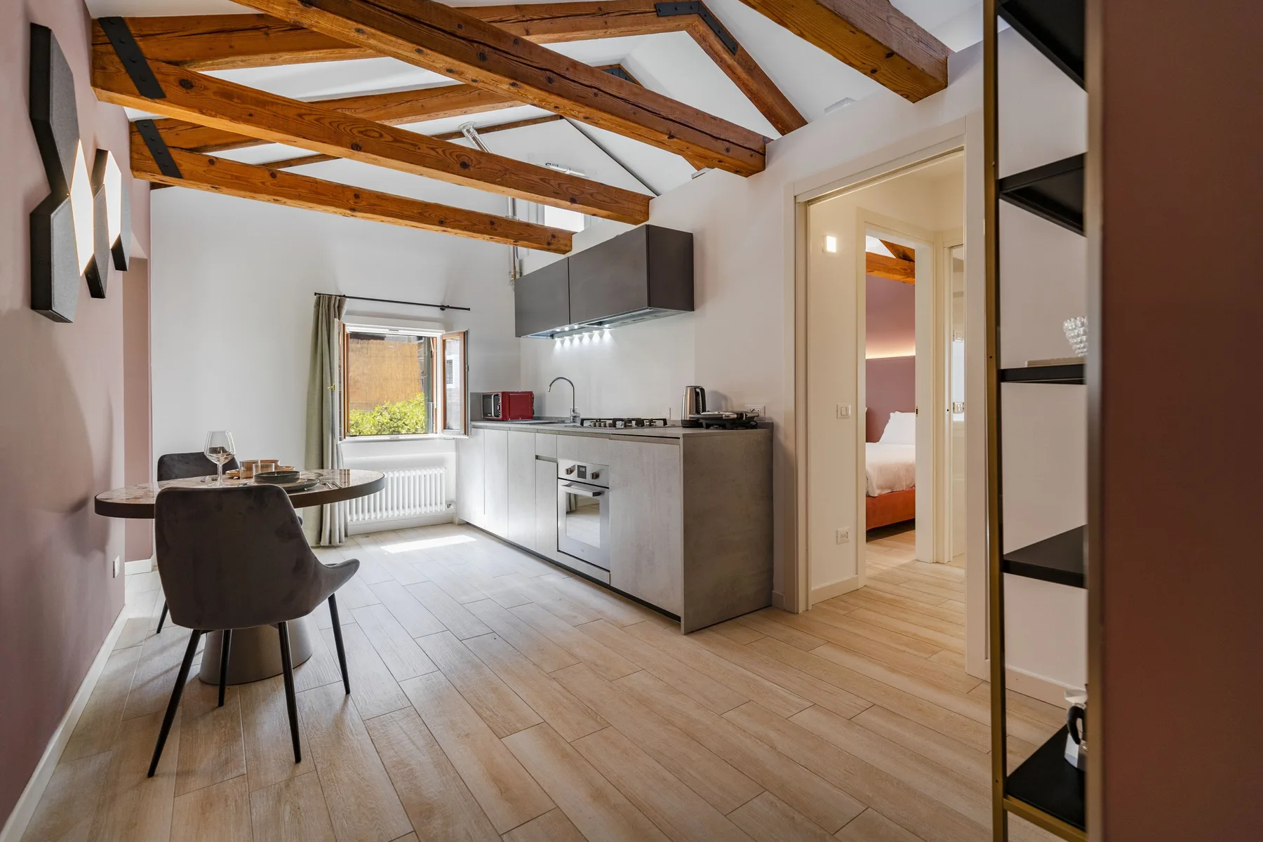 A bright kitchen and dining area with exposed wooden ceiling beams and a table.