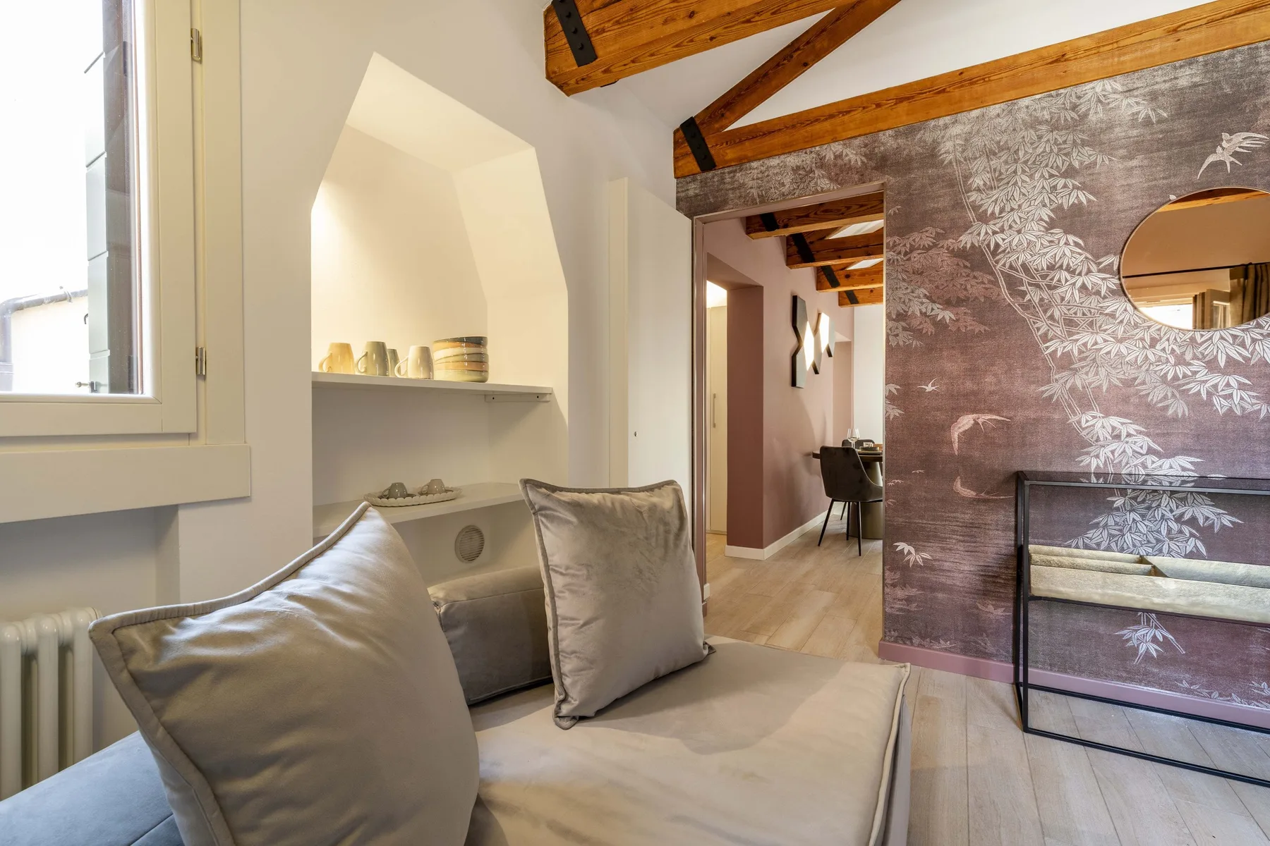 A bright sitting area with cushioned seating, a built-in niche, and exposed ceiling beams.