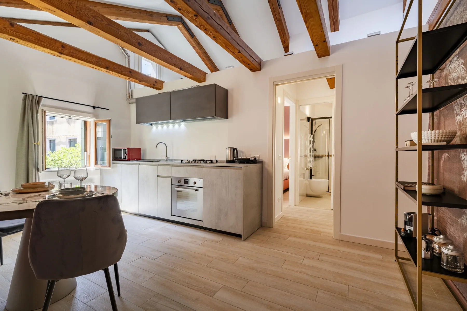 A kitchen and dining area with exposed ceiling beams and an open doorway.