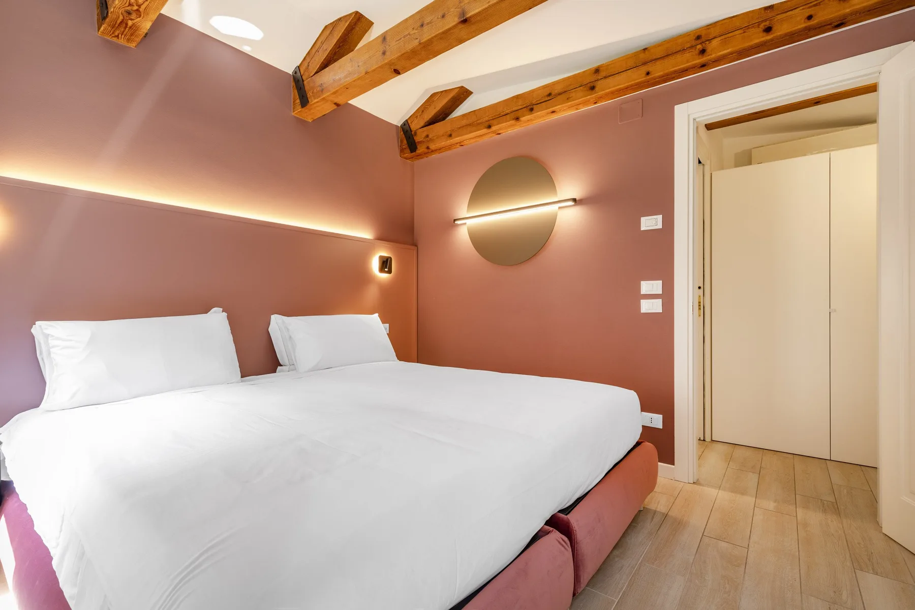 A bedroom with a large bed beneath exposed wooden ceiling beams.