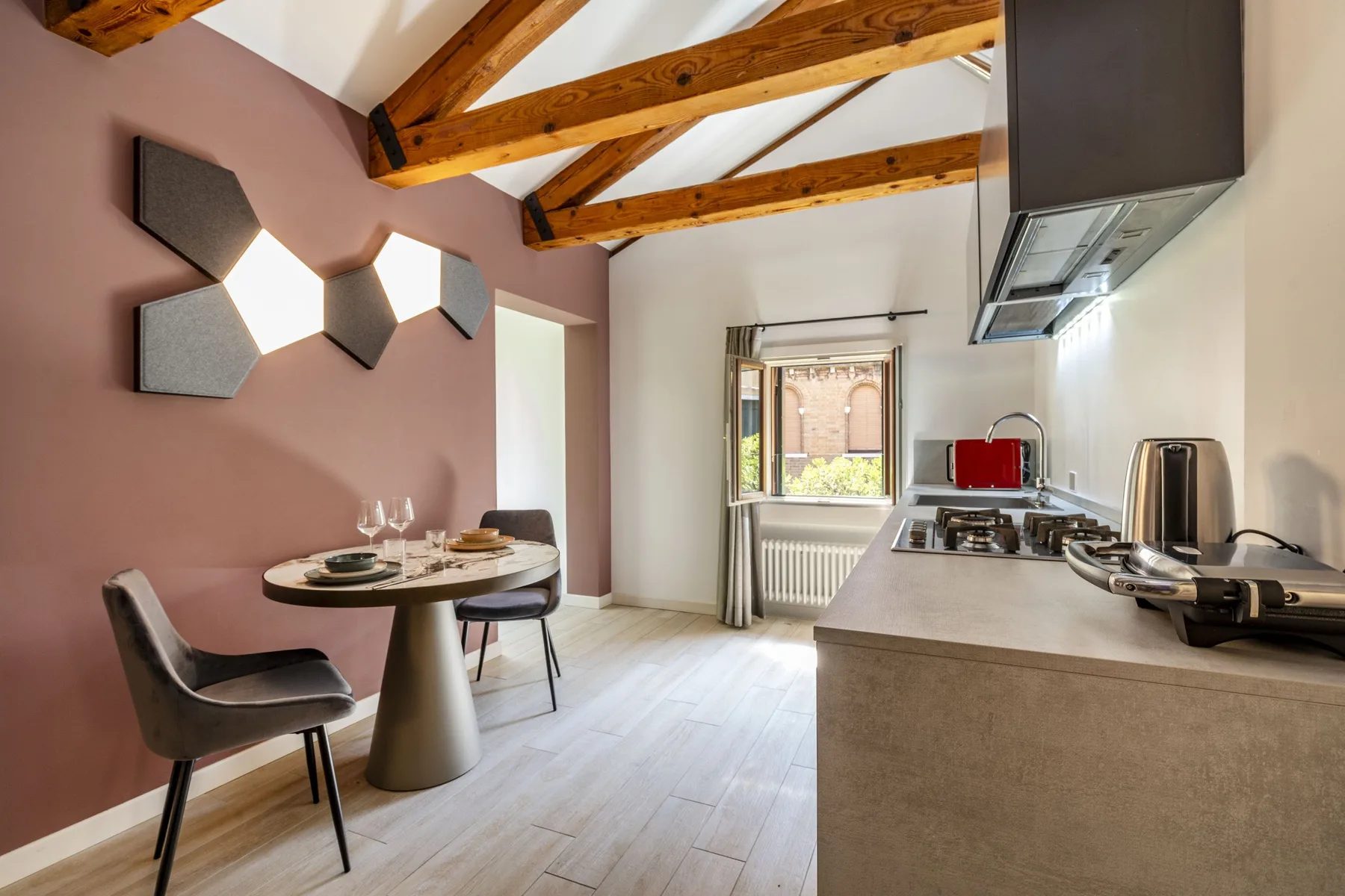 A dining area and kitchen sit beneath exposed wooden ceiling beams.