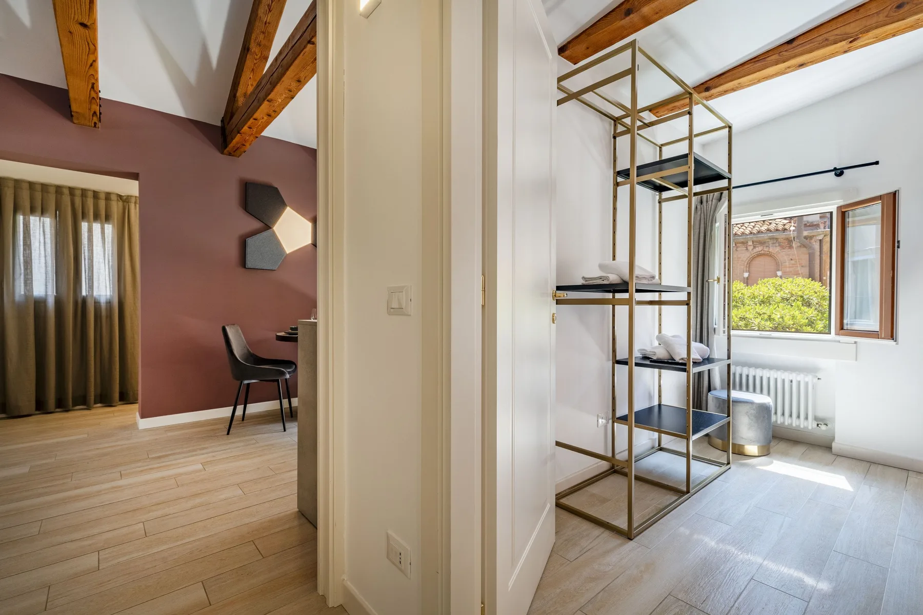 A bright bedroom area with a window, radiator, and open shelving.