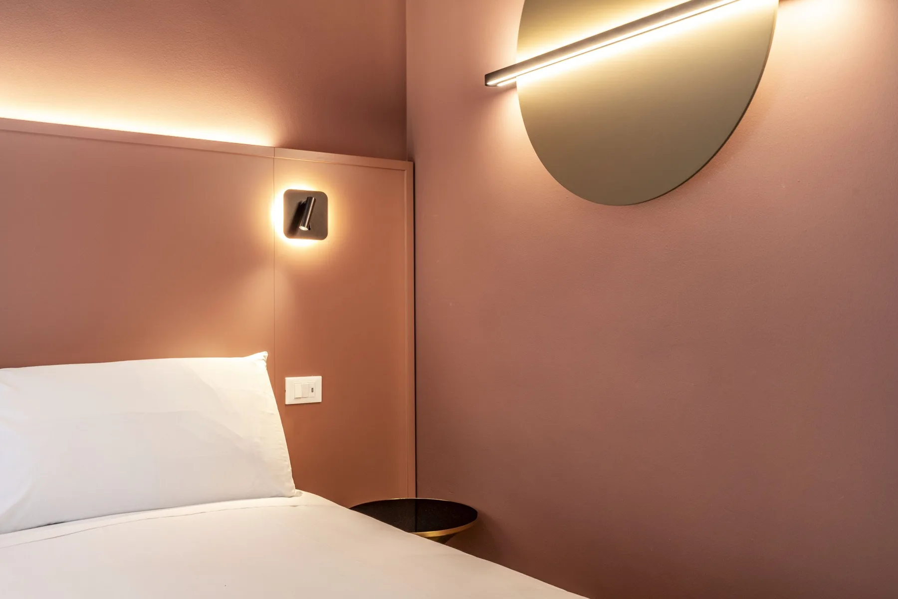 A bedroom with a bed and warm wall lighting.