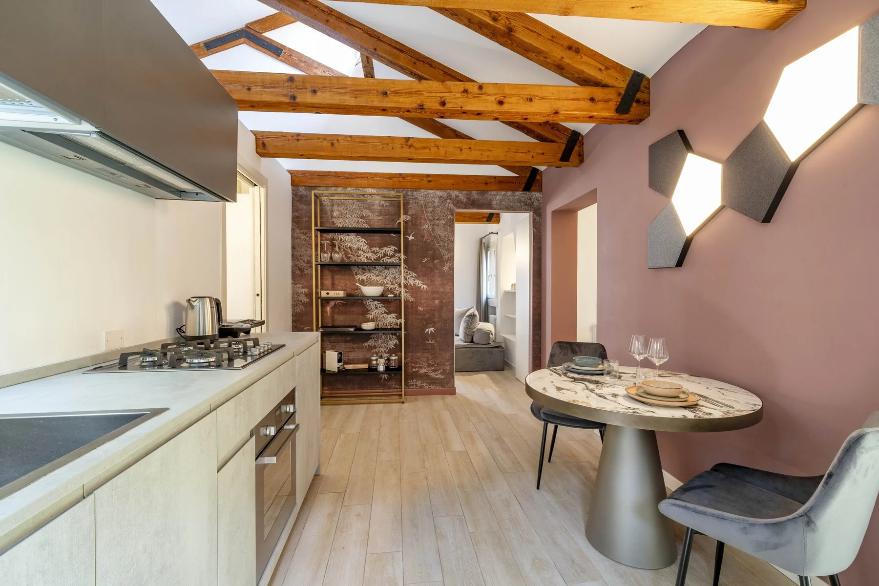 An open-plan kitchen and dining area with exposed wooden ceiling beams.