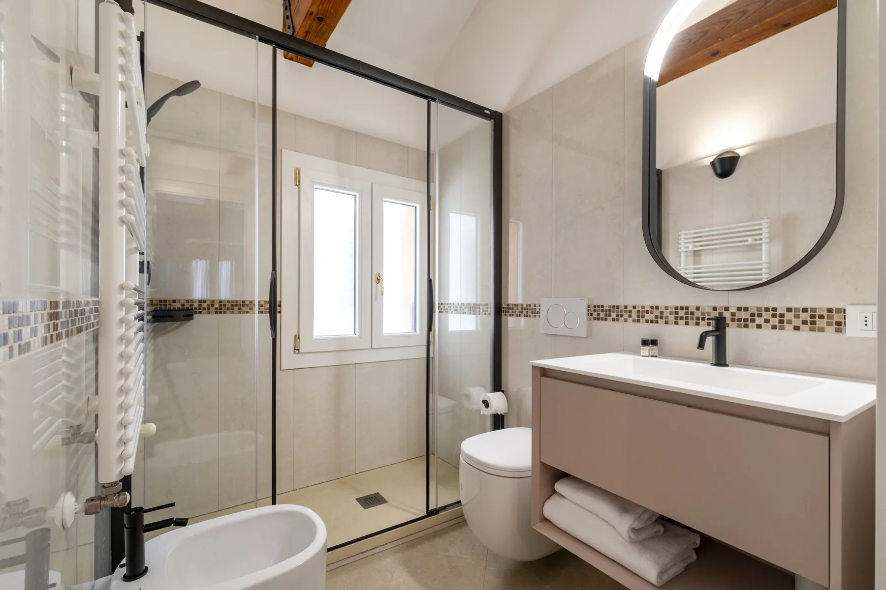 A modern bathroom with a glass shower, bathtub, toilet, and vanity.