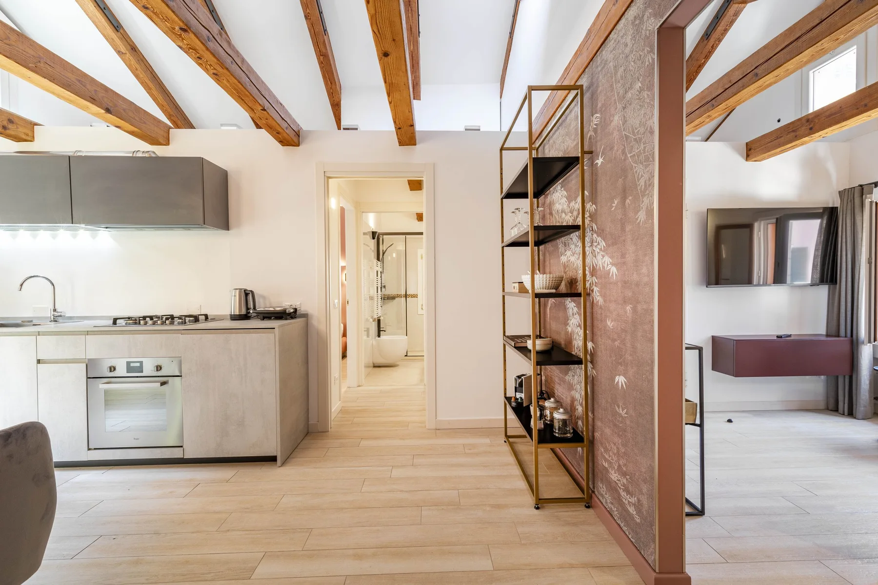 A bright open-plan kitchen and living area with exposed wooden ceiling beams.