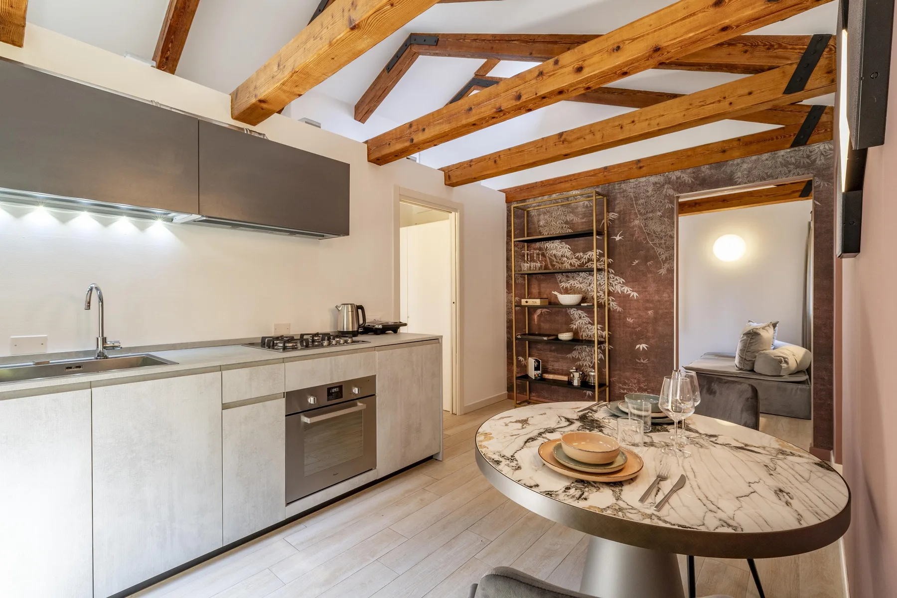 A kitchen and dining area with exposed wooden beams and a round table.