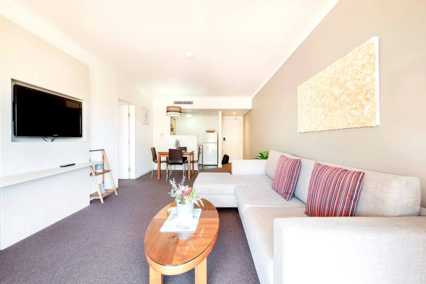 A bright living room with a light-colored sofa and an oval coffee table.