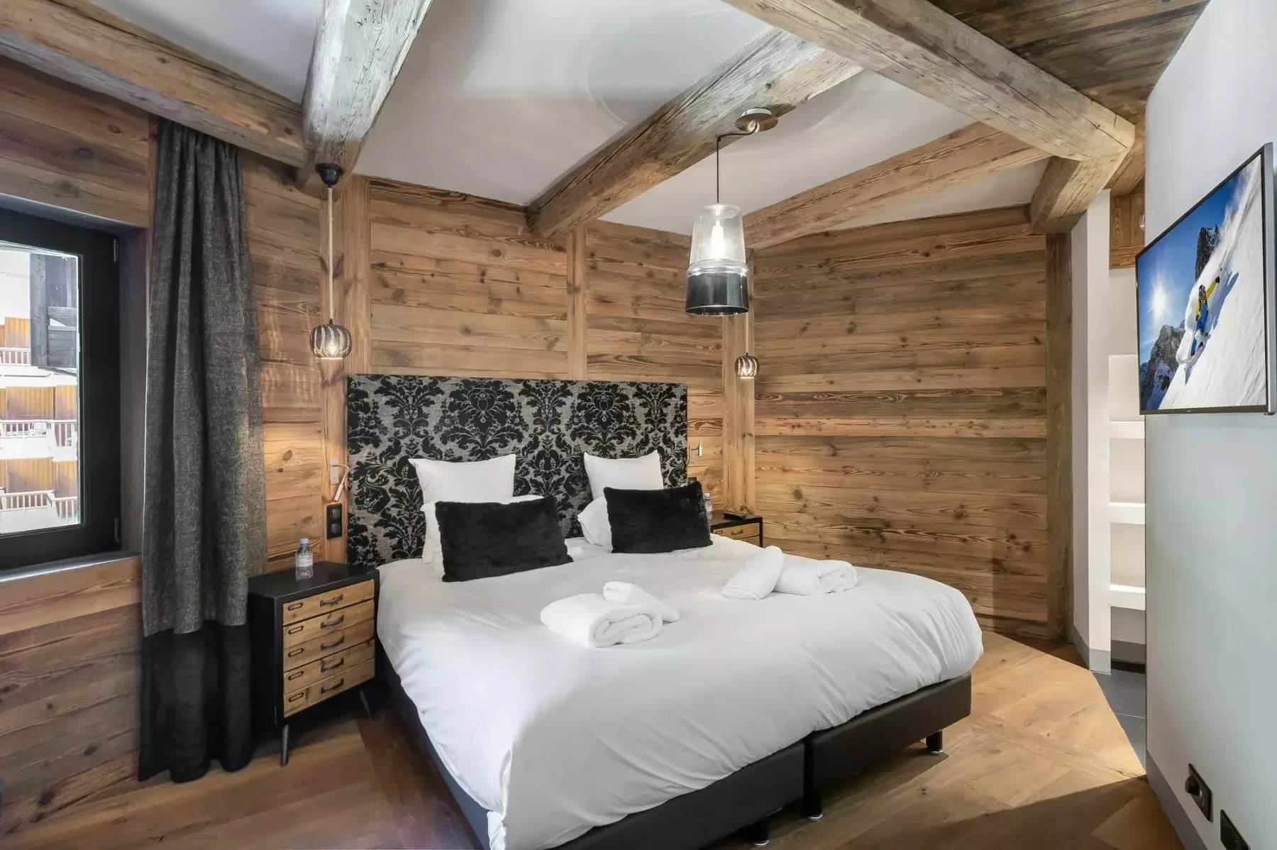 A bedroom with a white bed against wood-paneled walls.