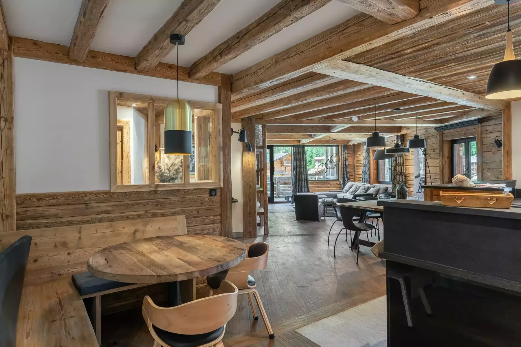 A rustic dining and lounge area with wooden tables and exposed beams.