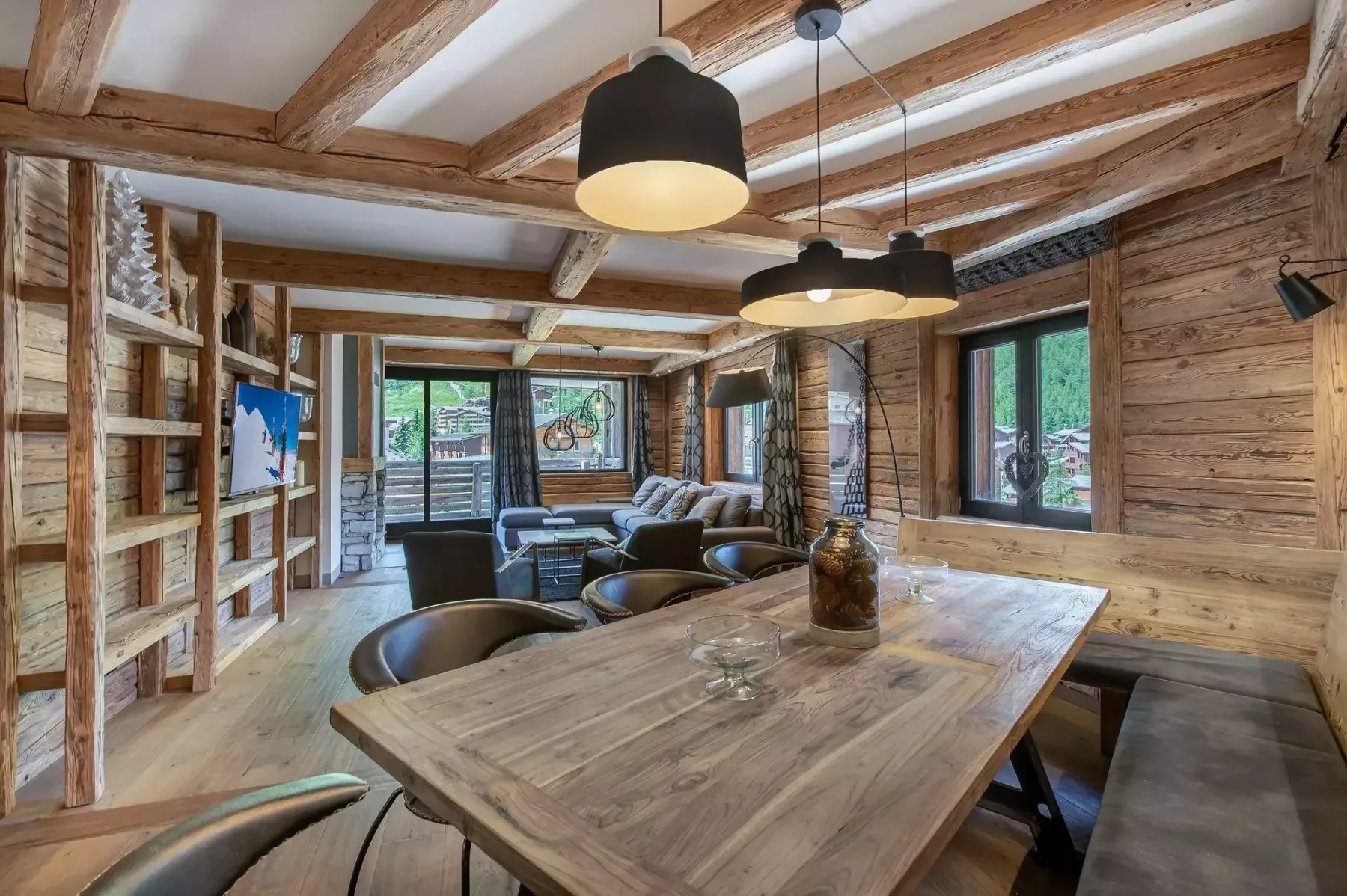 A wood-paneled dining area with a large table, bench seating, and exposed ceiling beams.