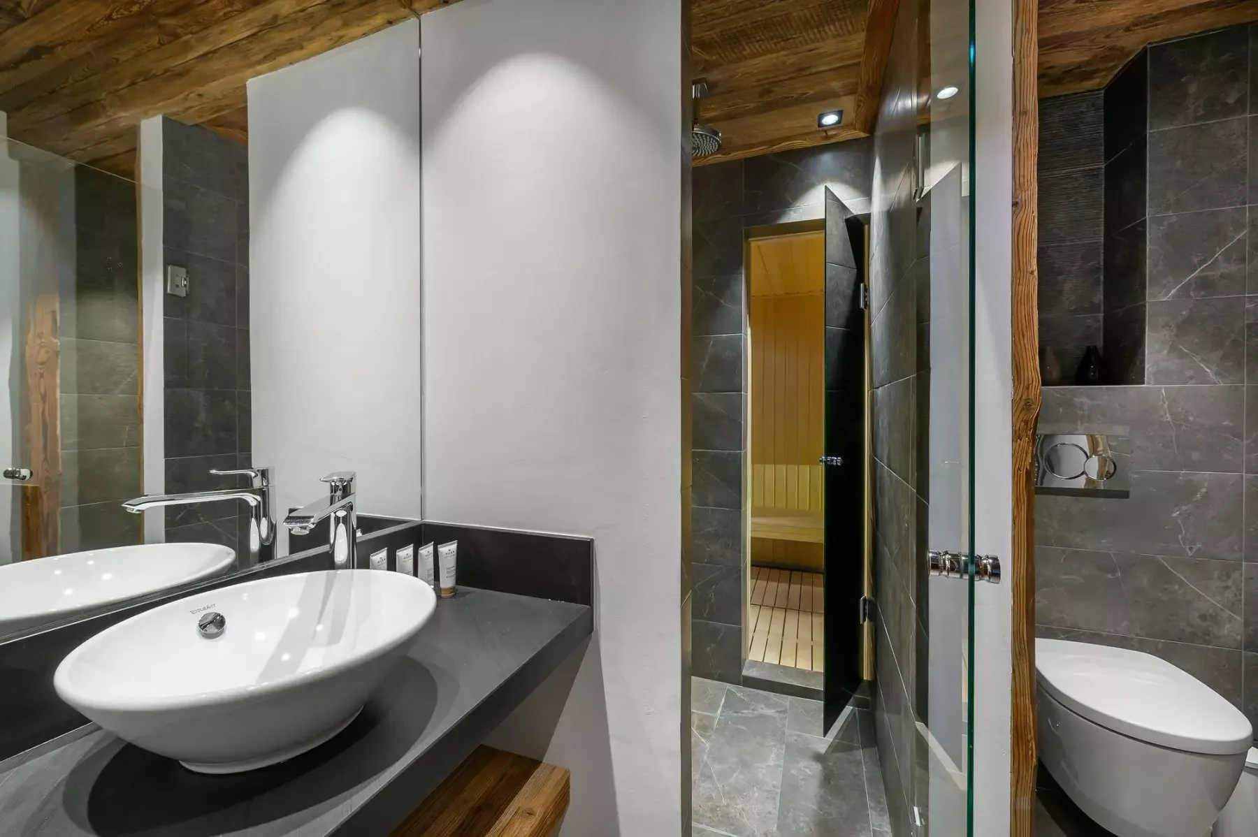 A modern bathroom with a sink, glass shower, and toilet.