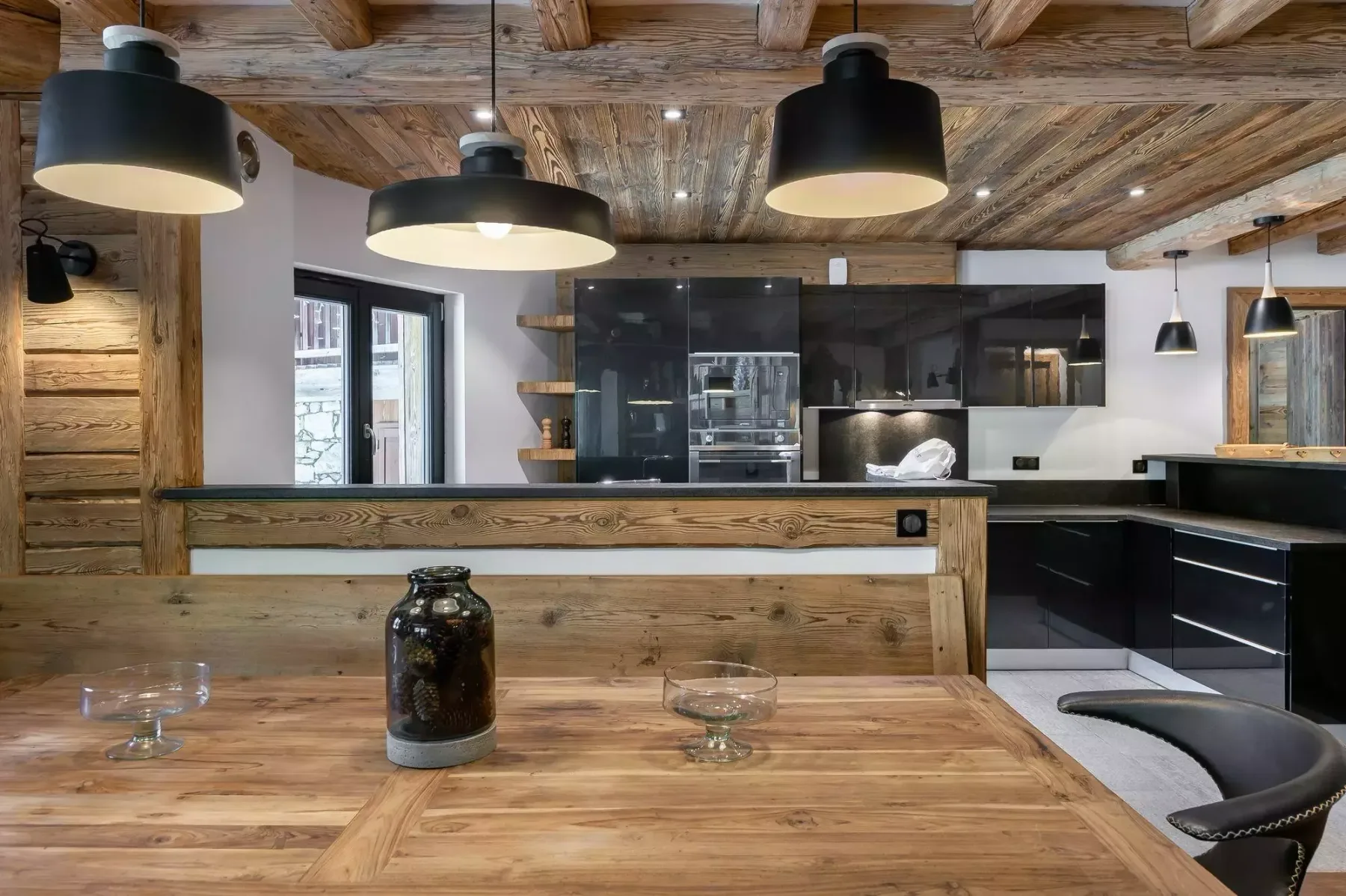 A rustic kitchen with a wooden dining table and dark cabinetry.